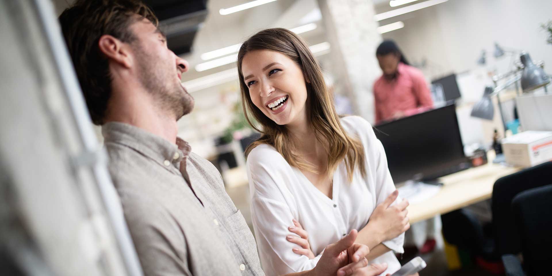 Two people laughing and talking in an office